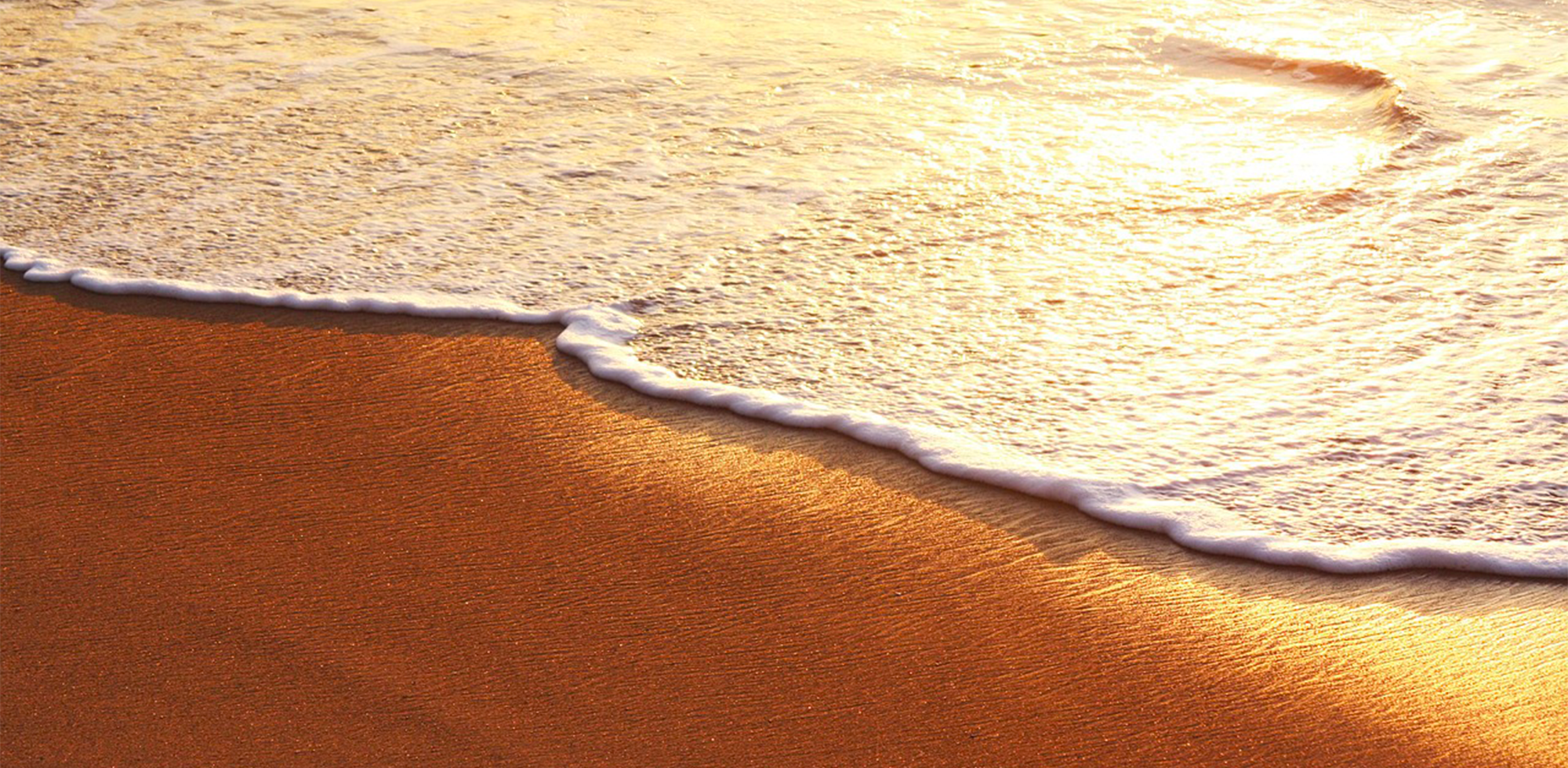 Vagues de l’océan Atlantique au coucher du soleil sur une plage du Sud-Ouest, lumière dorée sur le sable.